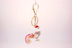 Detail of golden rooster keychain with white rhinestones and colorful enamel tail