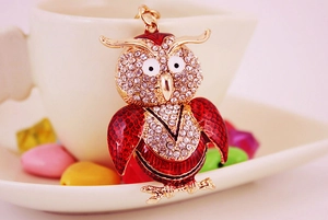 Macro d'un porte-clés hibou avec strass étincelants et émail rouge sur tasse blanche