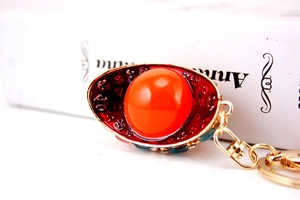 Detail of creative Chinese style gold keychain with orange crystal gem and red enamel