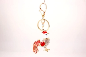 Detailed view of rooster keychain with gold metal base, enamel glaze and rhinestones