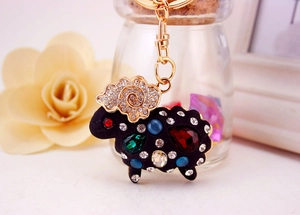 Gros plan d'un porte-clés mouton avec strass colorés et fermoir en métal doré sur fond floral