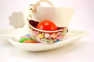 Detailed macro view of a gold-toned crystal ingot keychain hanging on a white ceramic cup