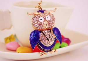 Détail d'un porte-clés hibou en émail bleu et cristaux sur le bord d'une tasse en céramique