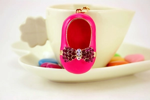 Macro shot of pink enamel shoe keychain with purple crystal bow and gold metal ring