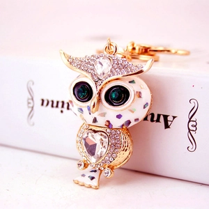 Porte-clés chouette doré orné de strass brillants et émail blanc sur fond épuré blanc