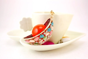 Detail view of a colorful rhinestone pendant hanging on a white coffee cup handle