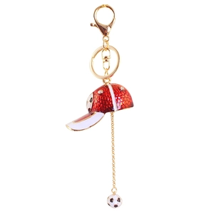 Golden keychain with a red textured baseball cap and a black and white soccer ball pendant