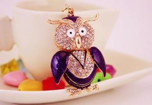 Détail de porte-clés hibou avec ailes en émail violet et cristaux scintillants