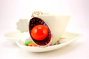 Detail of red rhinestone crystal ingot keychain with gold metal frame and ornate red gems