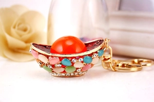 Close-up of golden Chinese ingot keychain with colorful opal stones and crystals