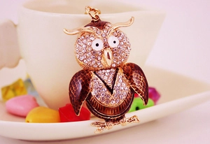 Détail du porte-clés hibou avec strass blancs et émail brun sur bord de tasse céramique