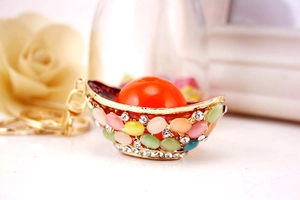 Macro shot of gold yuanbao keychain with colorful cat eye stones and sparkling crystals