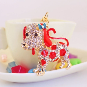 Sparkly rhinestone puppy keychain with red enamel spots and blue bow on a gold ring