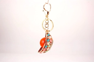 Macro detail of golden metal hat keychain with colorful rhinestones and orange pearl