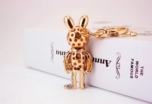 Detail view of gold rabbit keychain with rhinestone paw and metal ring on white book