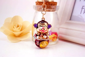 Close-up of golden monkey keychain with purple enamel, pearls and Fu character detail