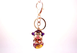 Detail of cute golden monkey keychain with purple enamel and 福 character lucky bag