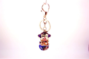 Close-up of golden cartoon monkey keychain with enamel blue treasure pot and fortune symbol