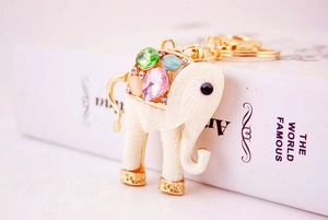 Detail of golden elephant keychain with colorful gemstones on a white book side