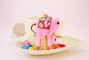 Detail showing a pink enamel elephant pendant with colorful gems on a ceramic heart plate