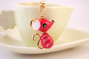 Détail d'un porte-clés souris en émail rouge avec strass blancs sur une tasse à café