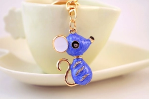 Vue détaillée du porte-clés souris en émail bleu sur le bord d'une tasse en céramique
