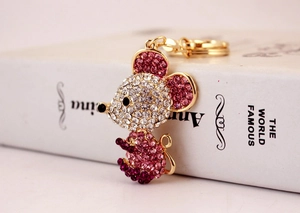 Macro detail of golden metal mouse keychain with sparkling white and purple crystals