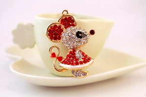 Detailed macro shot of a rhinestone mouse keychain with red bow on a heart ceramic plate