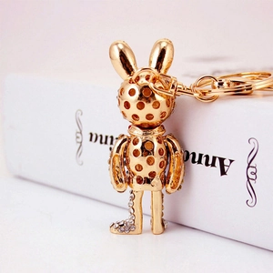 Creative hollow golden rabbit keychain with white rhinestones on a minimalist book