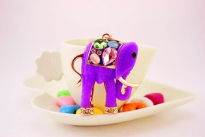 Detail of purple resin elephant pendant with colorful gemstones in a white heart tray