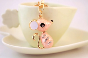 Vue macro d'un joli porte-clés souris en émail rose avec base dorée et strass brillants