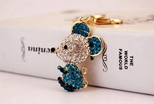 Macro shot of mouse keychain with sparkling sea blue crystals on golden alloy base