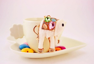 Detail of white elephant keychain with colorful resin gems and gold plating on cup