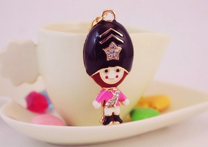 Detailed shot of a cute crystal Royal Guard keychain charm on a beige coffee cup background