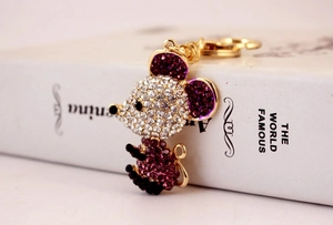 Close-up of golden mouse keychain featuring purple and white rhinestones on white background