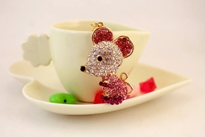 Detailed macro view of the gold-plated mouse pendant with pink and clear crystals
