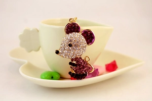 Detail of cute mouse keychain with white and magenta crystals on golden alloy base