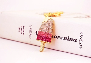 Close-up of pink gradient crystal popsicle keychain with gold lobster clasp on a book