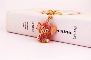 Macro shot of gold-plated elephant keychain with sparkling pink rhinestones on a white book