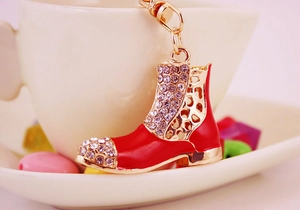 Dettaglio del portachiavi a stivaletto rosso con strass luminosi accanto a una tazza