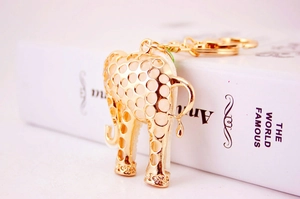 Detail of a gold elephant keychain with hollow dots on a white book edge