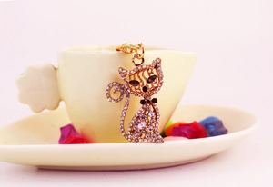 Détail d'un porte-clés chaton scintillant en strass posé sur une soucoupe de café blanc
