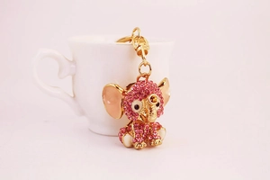 Detail of pink rhinestone elephant keychain with golden finish on white ceramic base