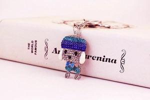 Detail shot of a sparkling crystal poodle keychain with blue rhinestones on an open book