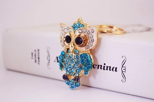 Détail du porte-clés hibou avec strass bleus sur base en métal doré et yeux en cristal noir