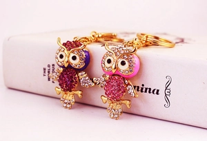 Close-up of dual owl keychains with colorful crystals and polished golden metallic details