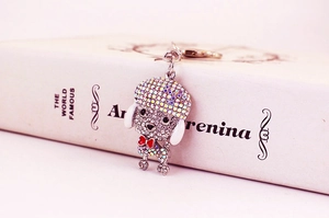 Detail of colorful rhinestone poodle keychain resting on an open book prop