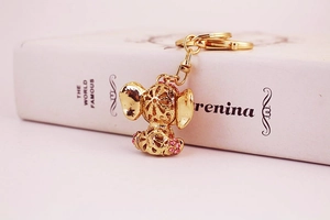 Detail of pink crystal elephant keychain with golden hardware on white book background