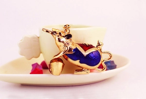 Close-up of golden mouse charm with blue enamel patterns and Chinese lucky coin detail