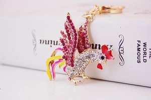 Detail of a sparkling crystal rooster keychain with pink rhinestones on a gold alloy body